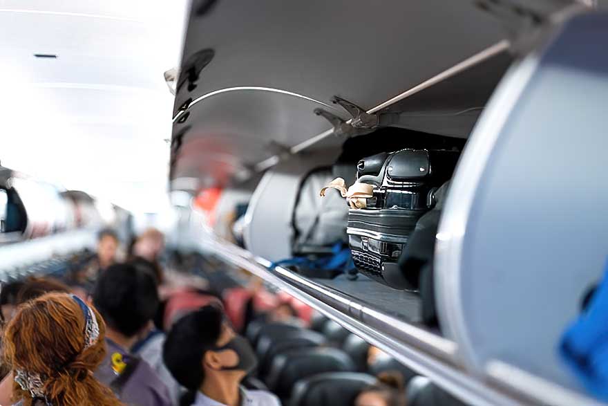 Why must airplane passengers place their luggage in the compartment above their seats?