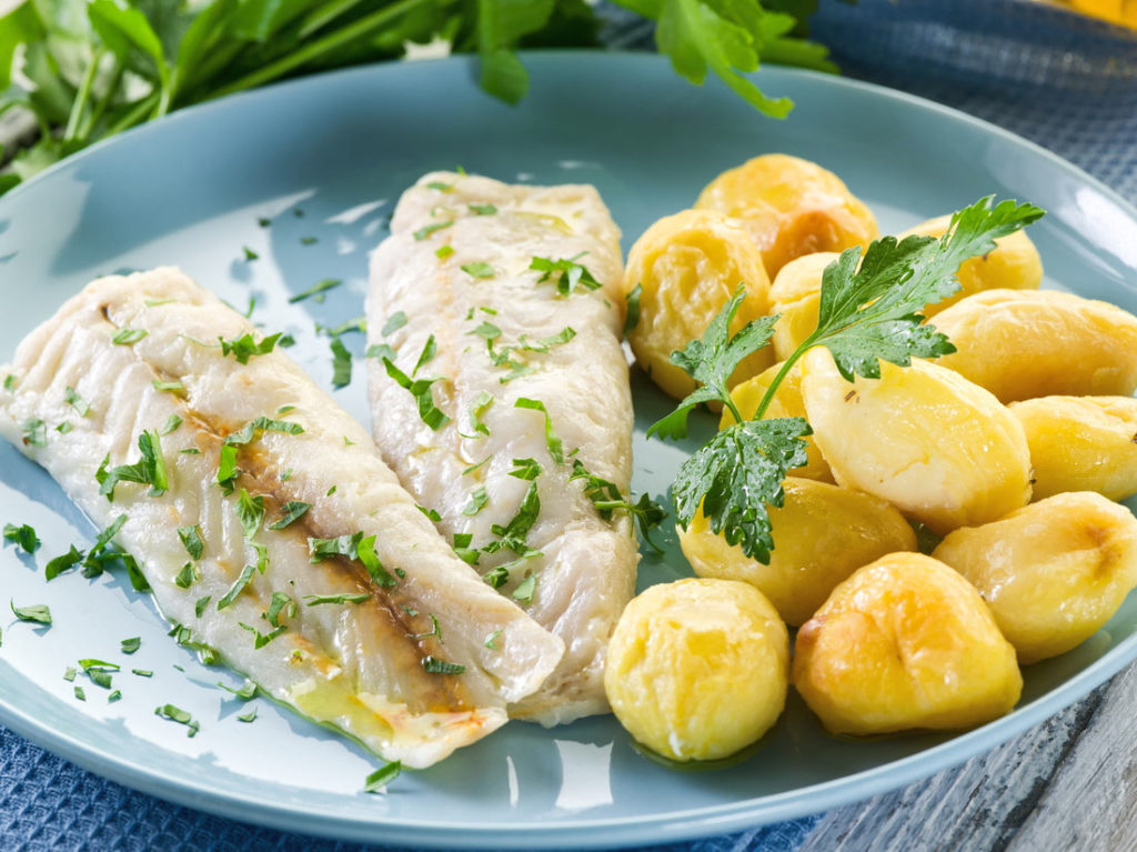 A healthy and flavorful dish featuring tender steamed cod, garnished with fresh parsley and served alongside buttery golden potatoes.