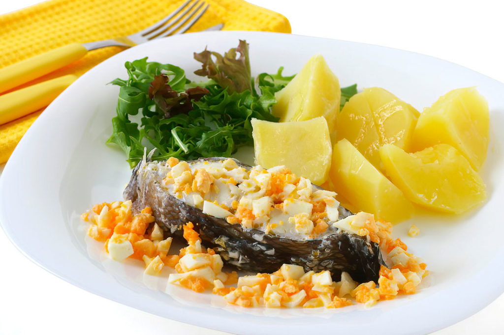 A simple and healthy dish featuring tender sea bass, buttery potatoes, and a rich topping of chopped hard-boiled eggs with a zesty lemon and olive oil finish.