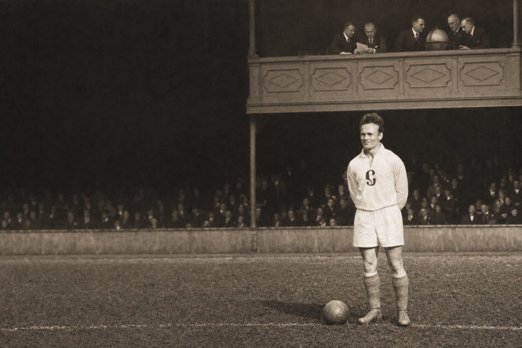 The player stands on the pitch while the decision-makers sit above: a visual metaphor for the institutions, officials and competing interests that govern world football.